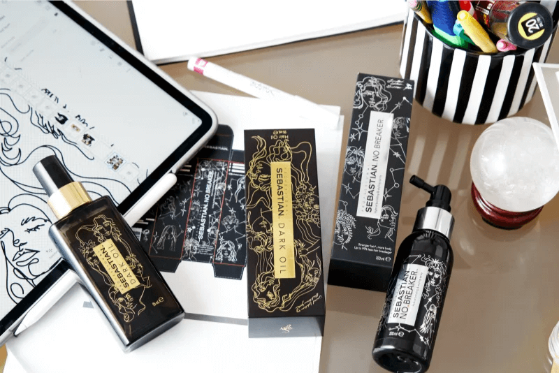 Sebastian Professional Dark Oil and No Breaker products on a desk with design tablet and stationery items.