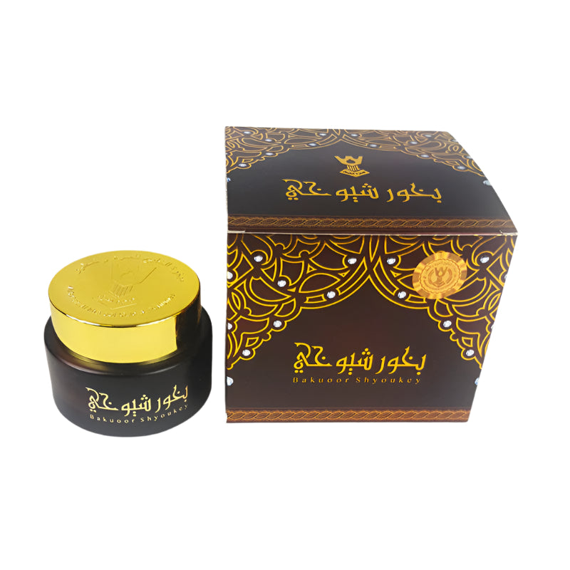 Black and gold cosmetic jar with decorative box on a white background