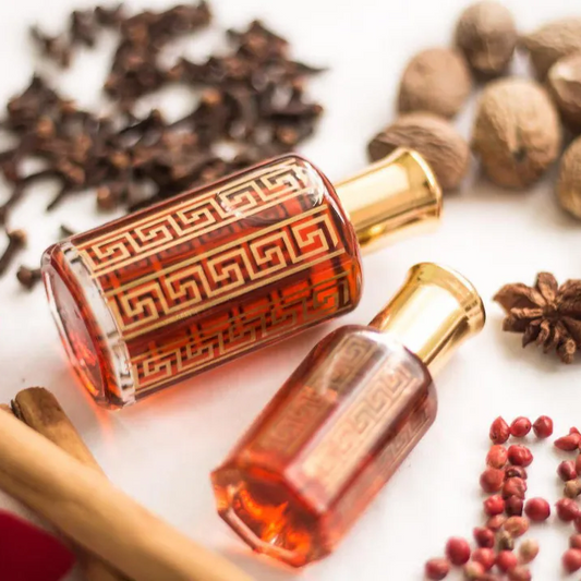 Two perfume bottles with a decorative design on a white background with spices and flowers.