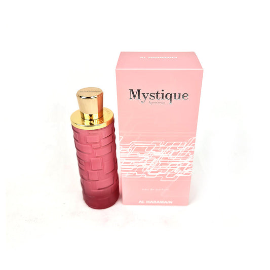 A pink Al Haramain Mystique Femme 100ml EDP bottle with a gold-colored cap, next to its pink packaging box.