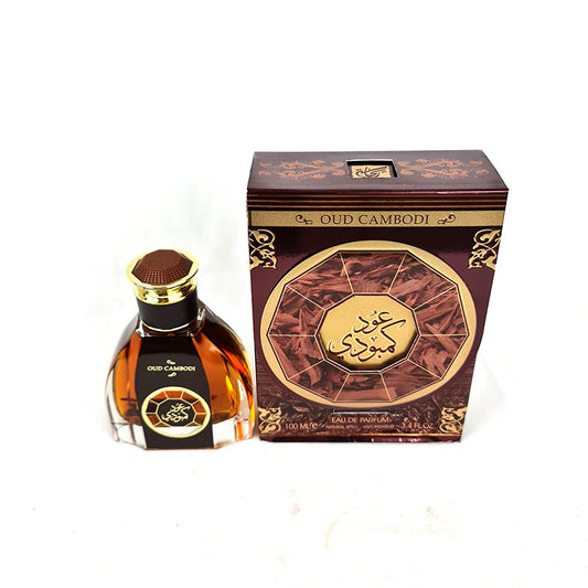A bottle of Oud Cambodi Unisex 100ml EDP by Rihanah next to its packaged box, both featuring a design with incense and agarwood symbols.