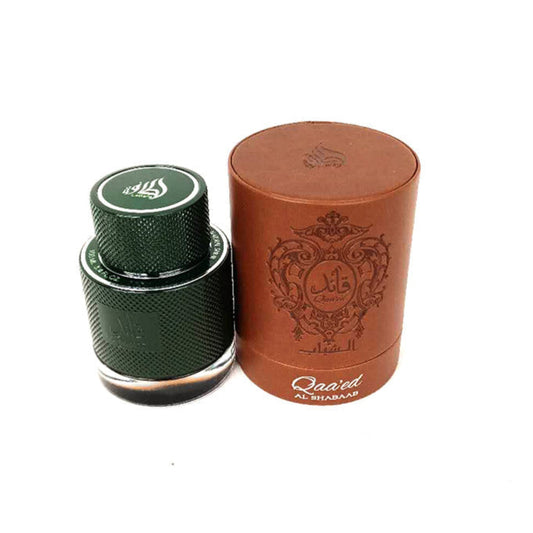 A perfume bottle with a green cap next to its brown cylindrical packaging box, both featuring Arabic script.