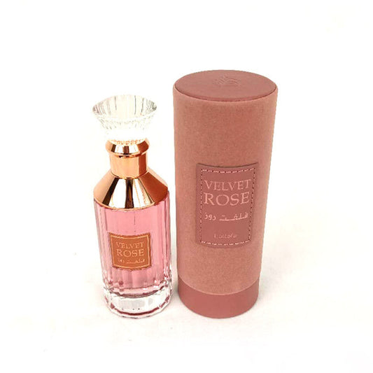 A bottle of Lattafa Perfume Velvet Rose Eau de Parfum with a pink label and a gold-colored cap, placed next to its brown packaging box.